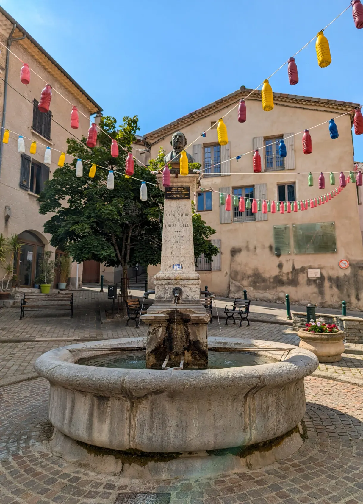 Fontaine ronde et guirlandes de fanions sur la place du village