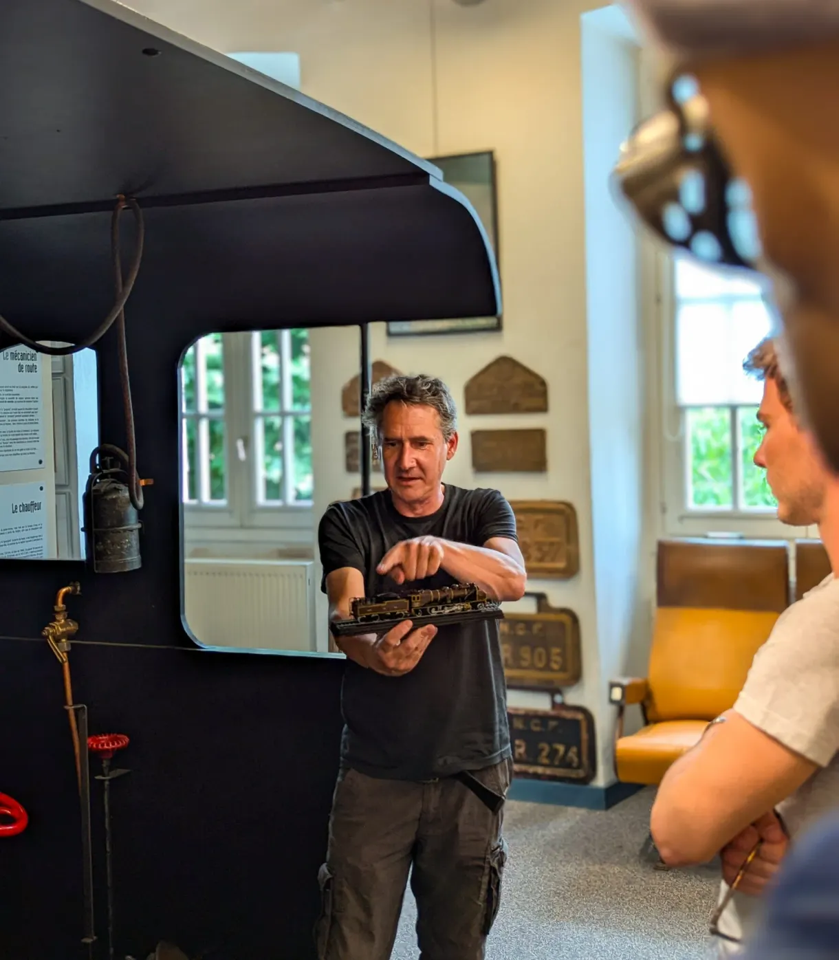Guide présentant des plaques de locomotive devant une machine noire