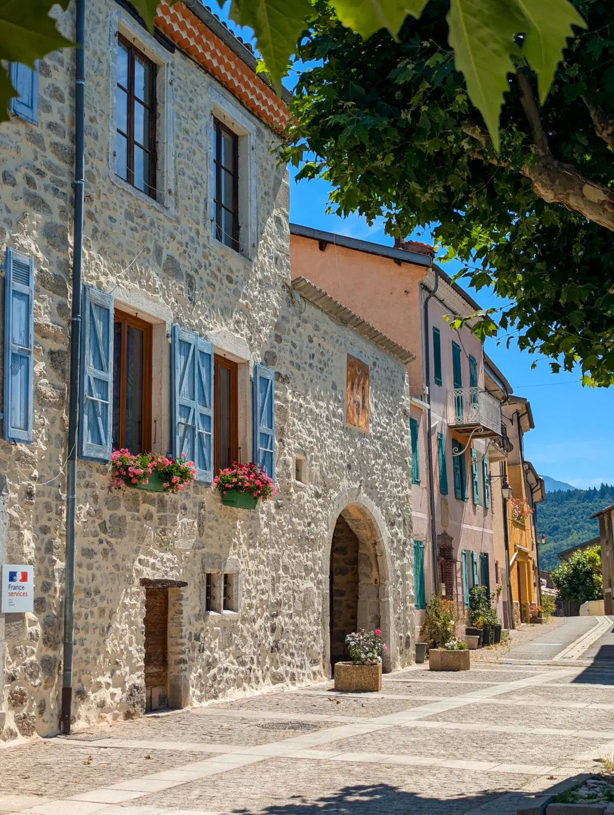 Rue pavée bordée de maisons de pierre aux volets bleus