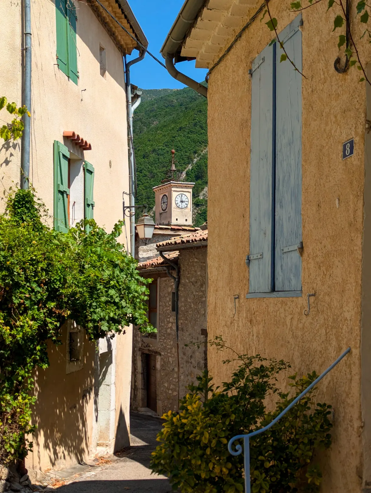 Ruelle étroite ouvrant sur le clocher à horloge du village