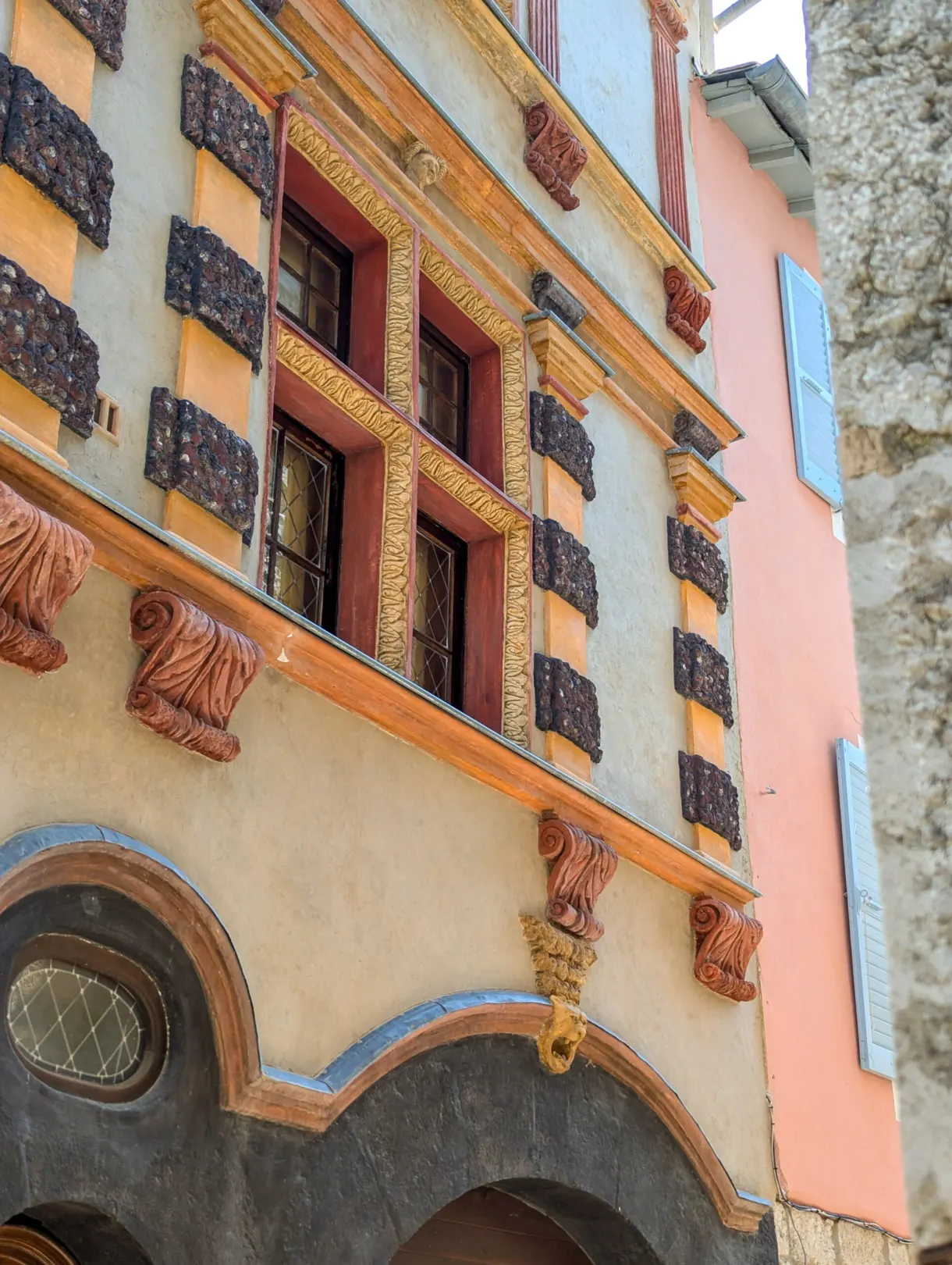 Détail de façade peinte en trompe-l'oeil aux encadrements rouges