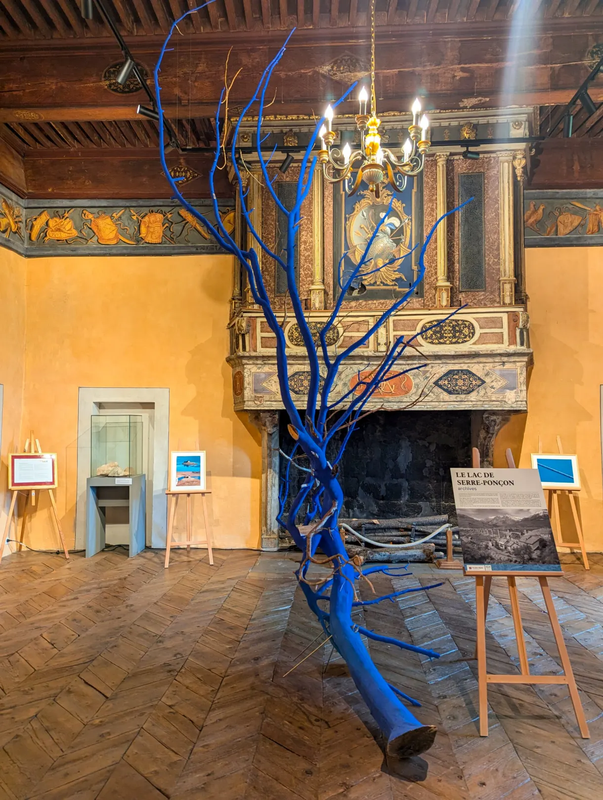 Sculpture d'arbre bleu installée devant la cheminée d'une salle peinte