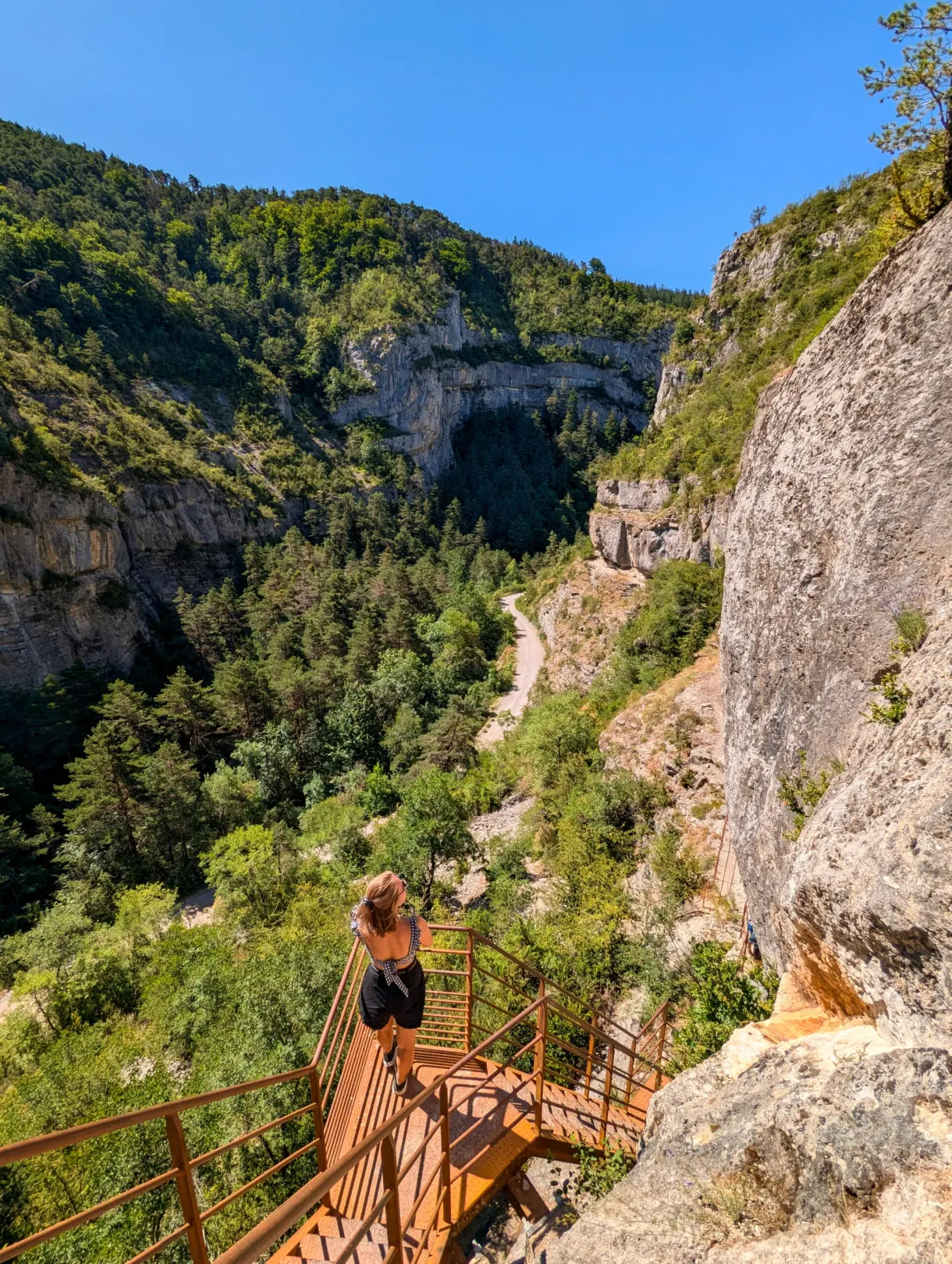 Randonneuse descendant l'escalier métallique accroché à la falaise