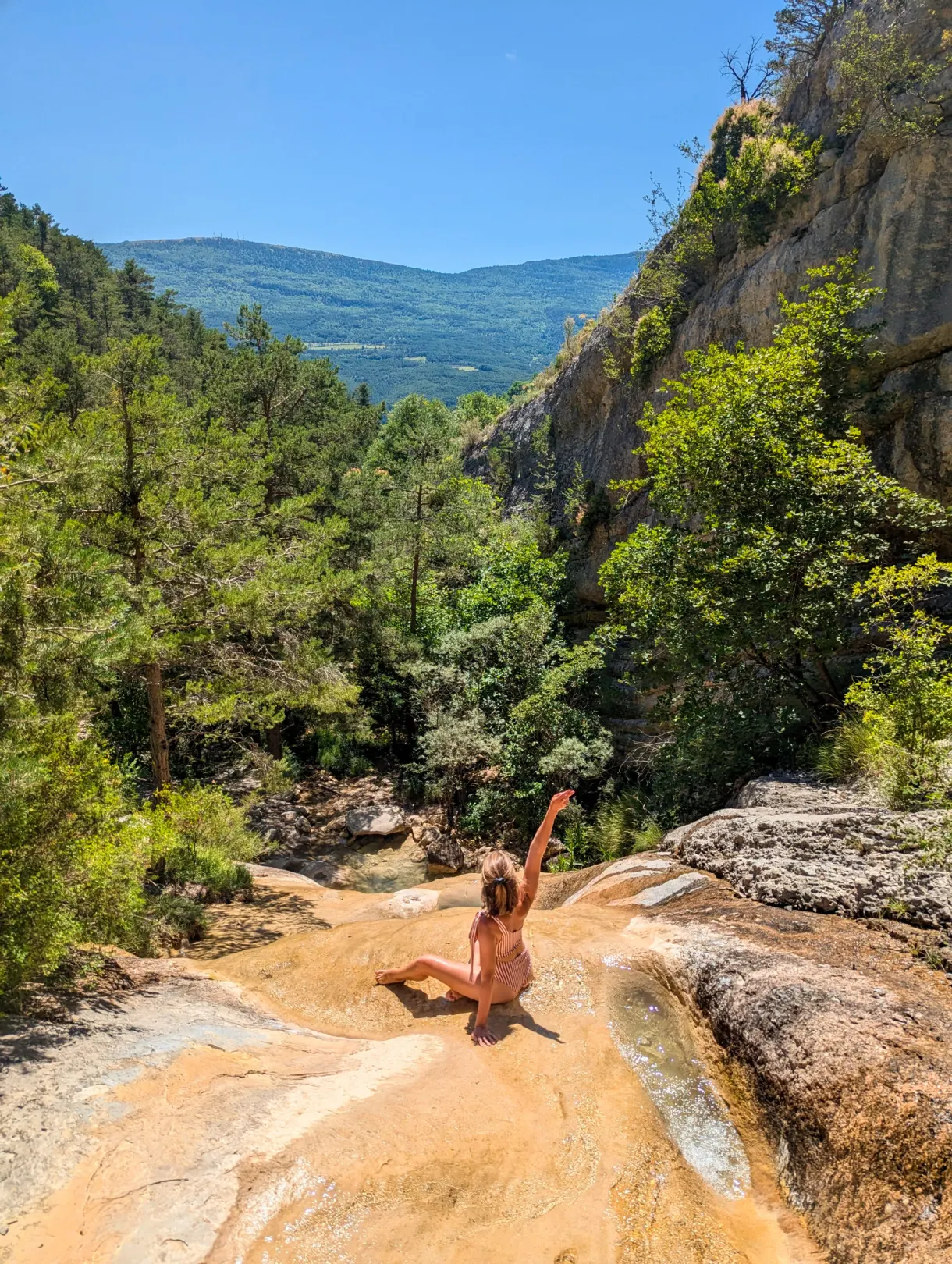 Baigneuse bras levés au milieu des dalles du torrent