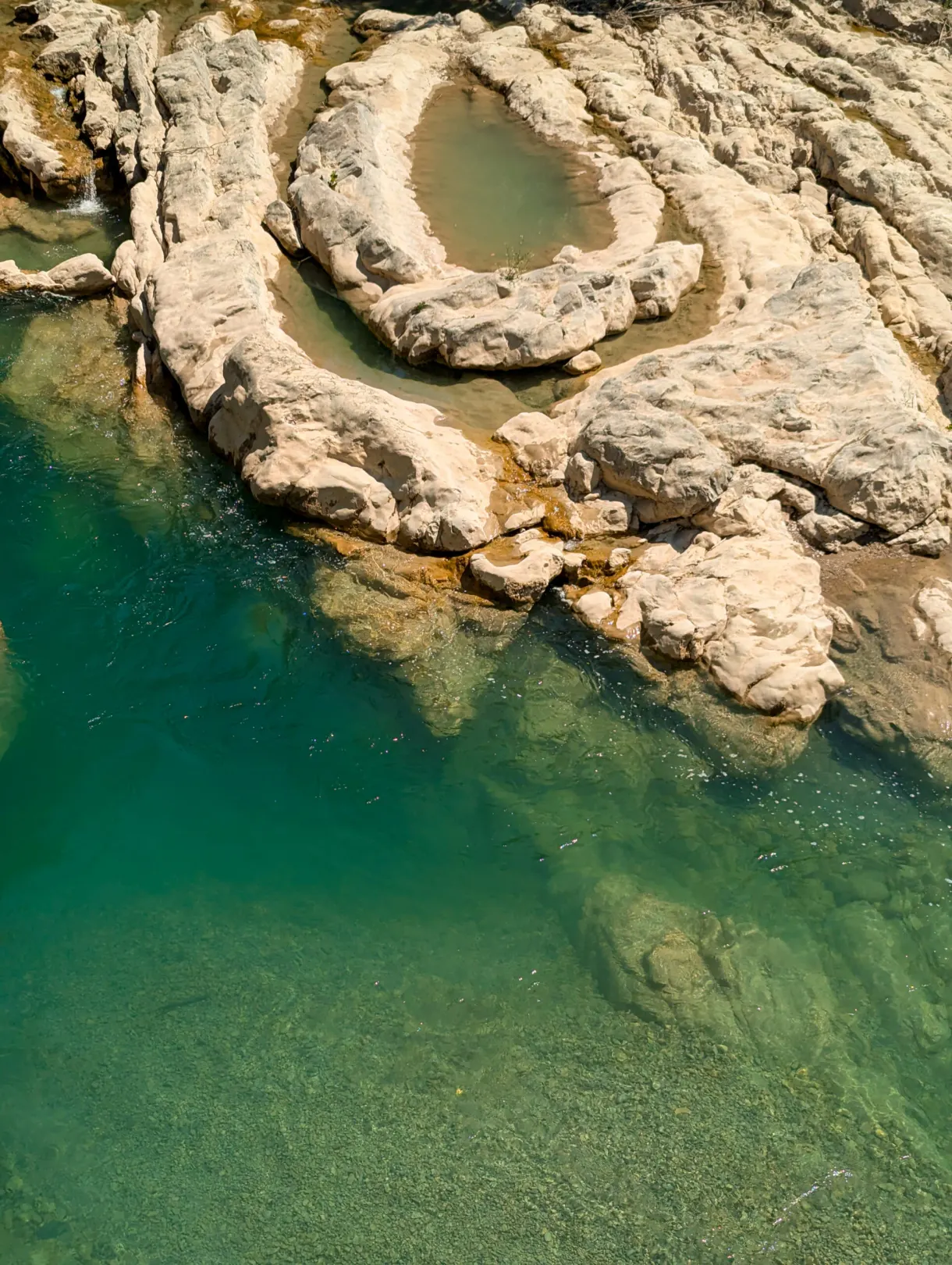 Vasque circulaire de roche blanche au bord d'une eau émeraude