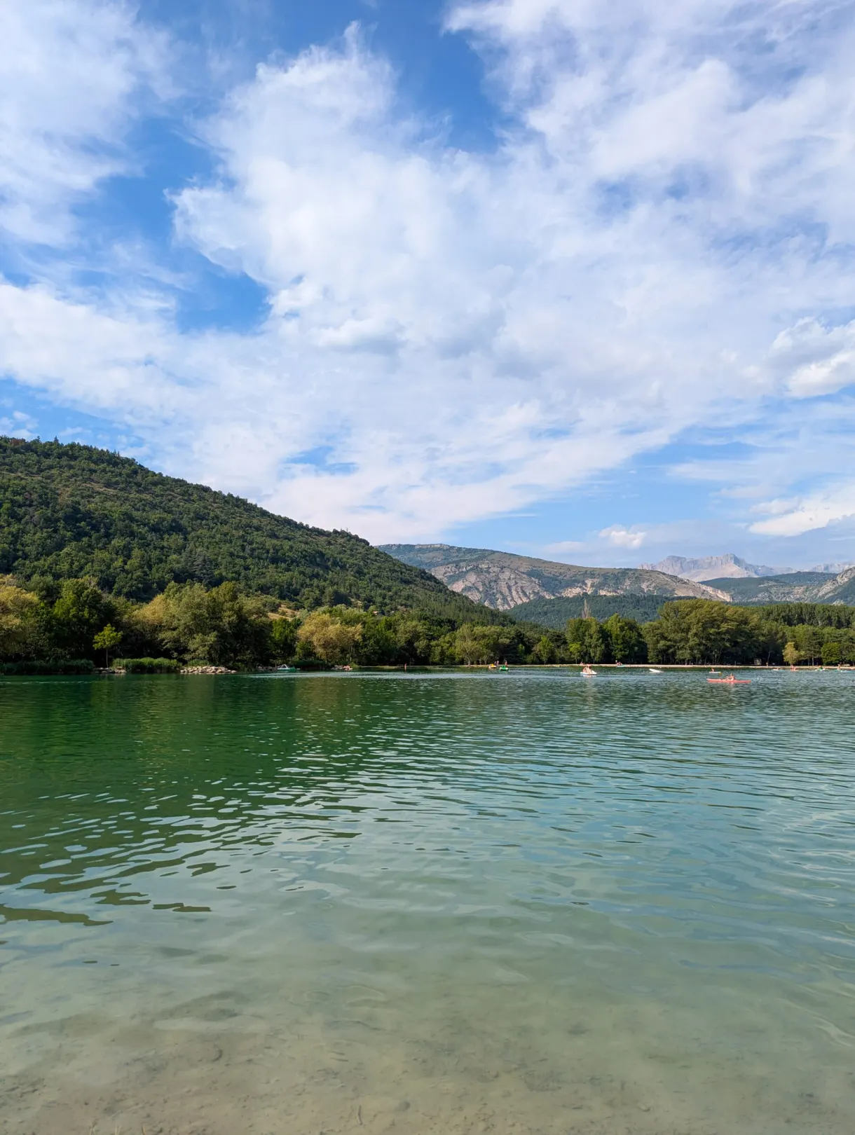 Lac calme et rive plantée d'arbres sous un ciel nuageux