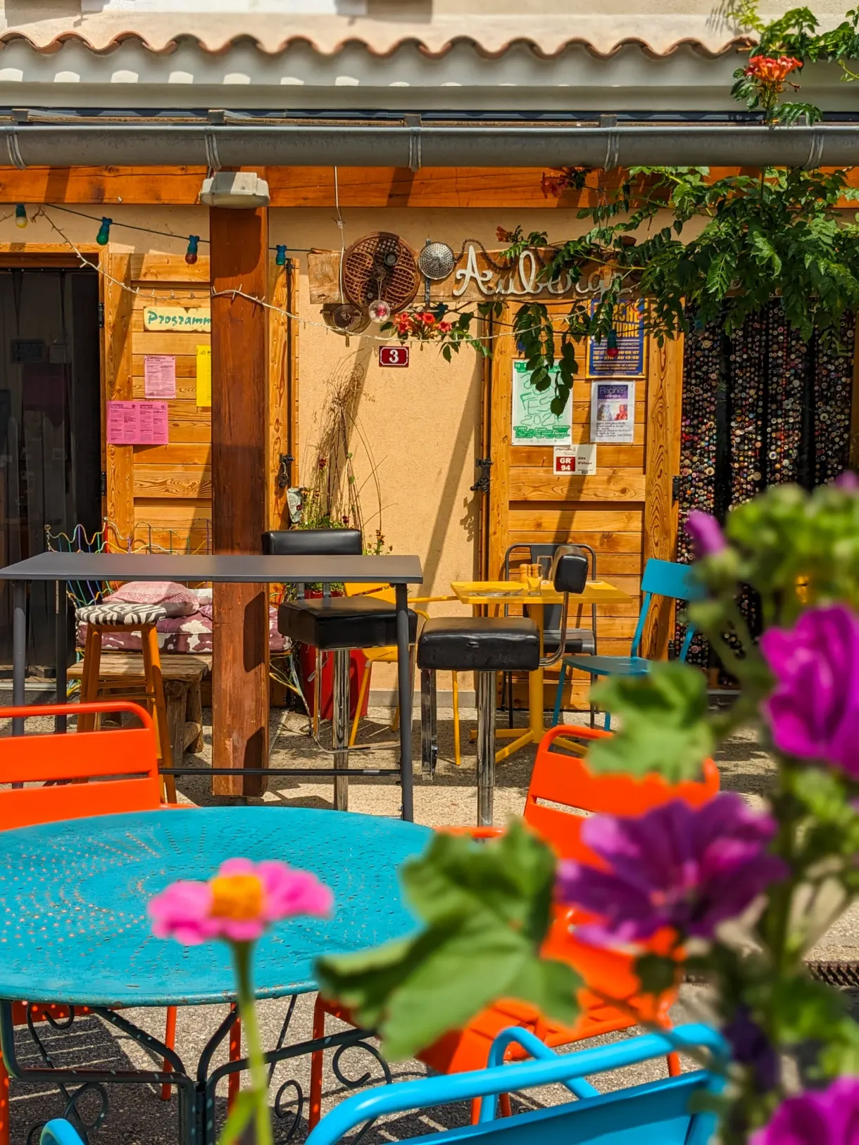 Terrasse aux tables turquoise et fleurs en pot devant le restaurant