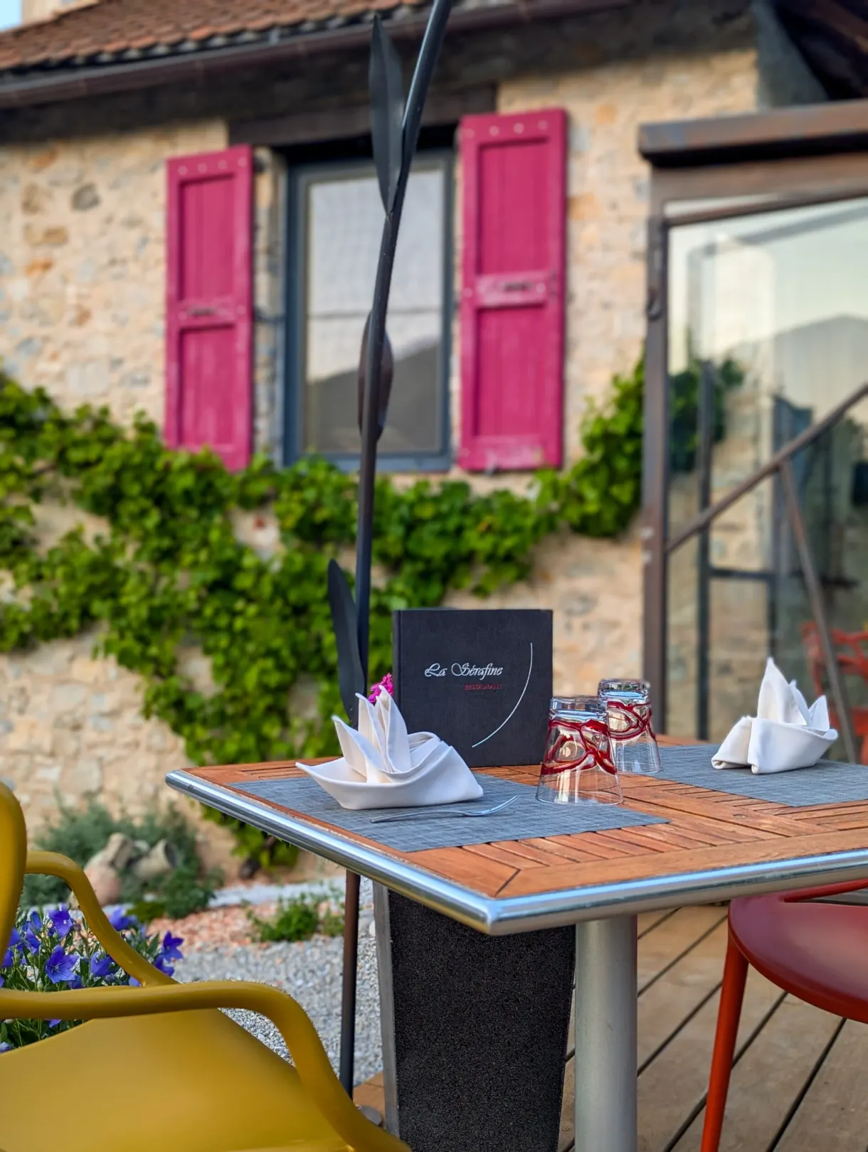 Table dressée en terrasse devant une façade aux volets roses