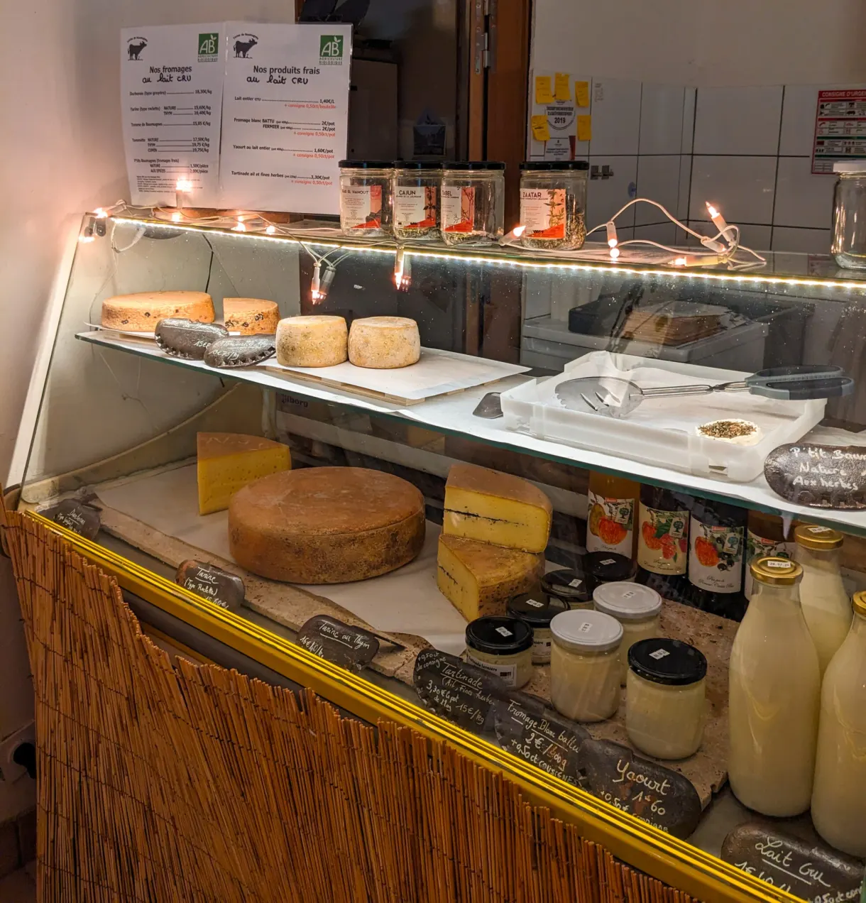 Vitrine réfrigérée garnie de meules, de tommes et de pots de lait