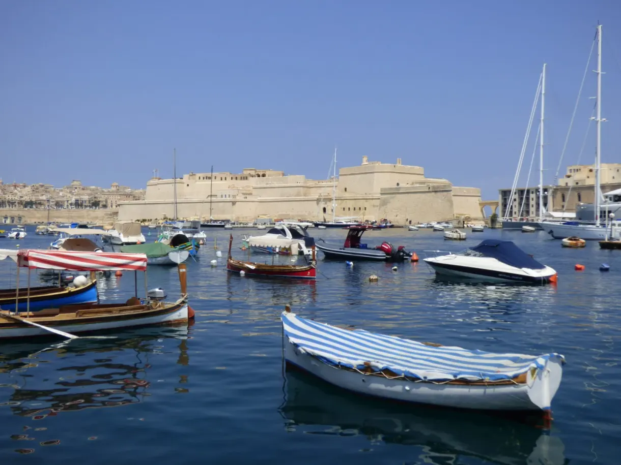 Barques maltaises colorées flottant devant les fortifications