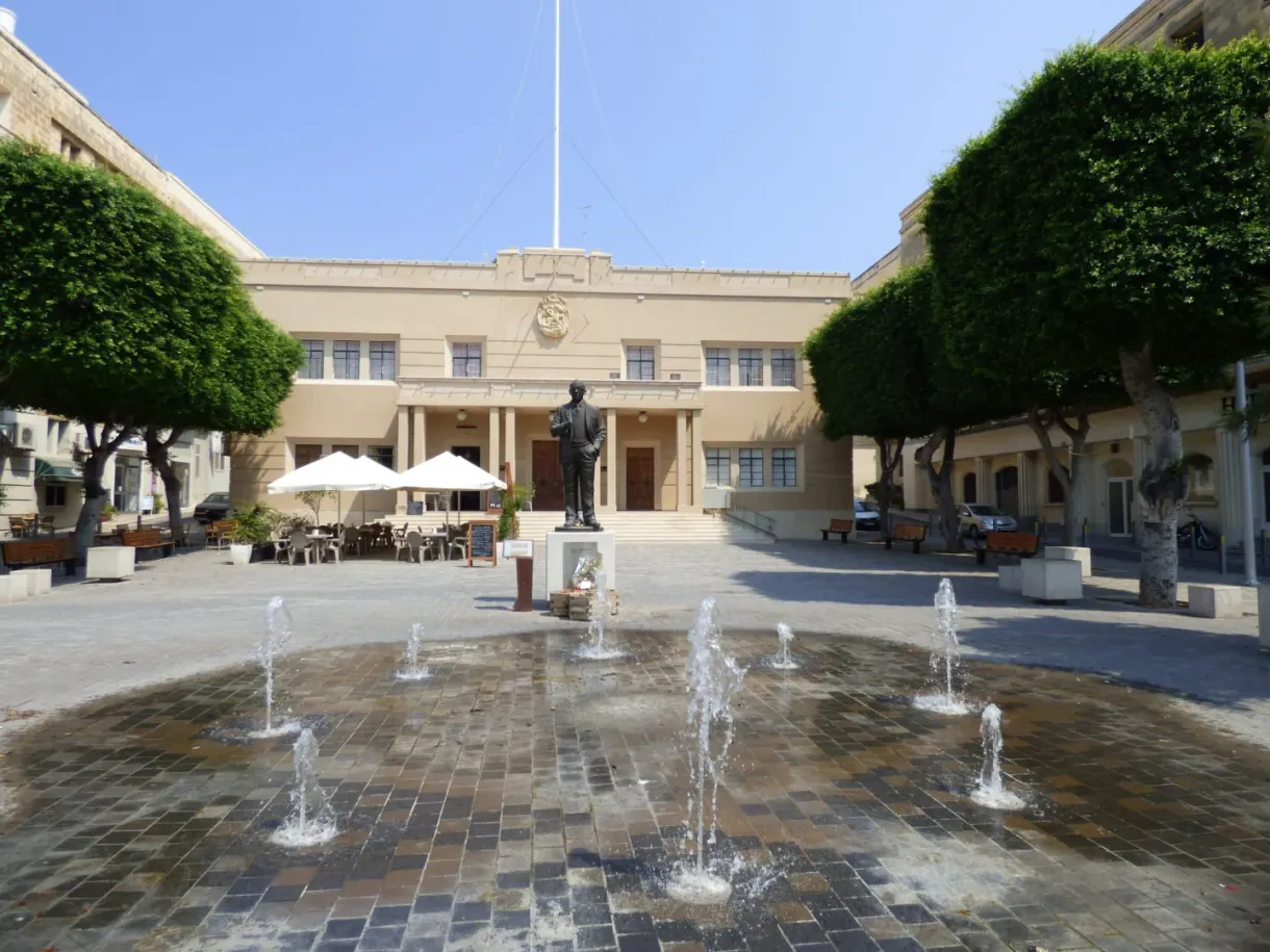 Jets d'eau d'une fontaine au milieu d'une place ombragée