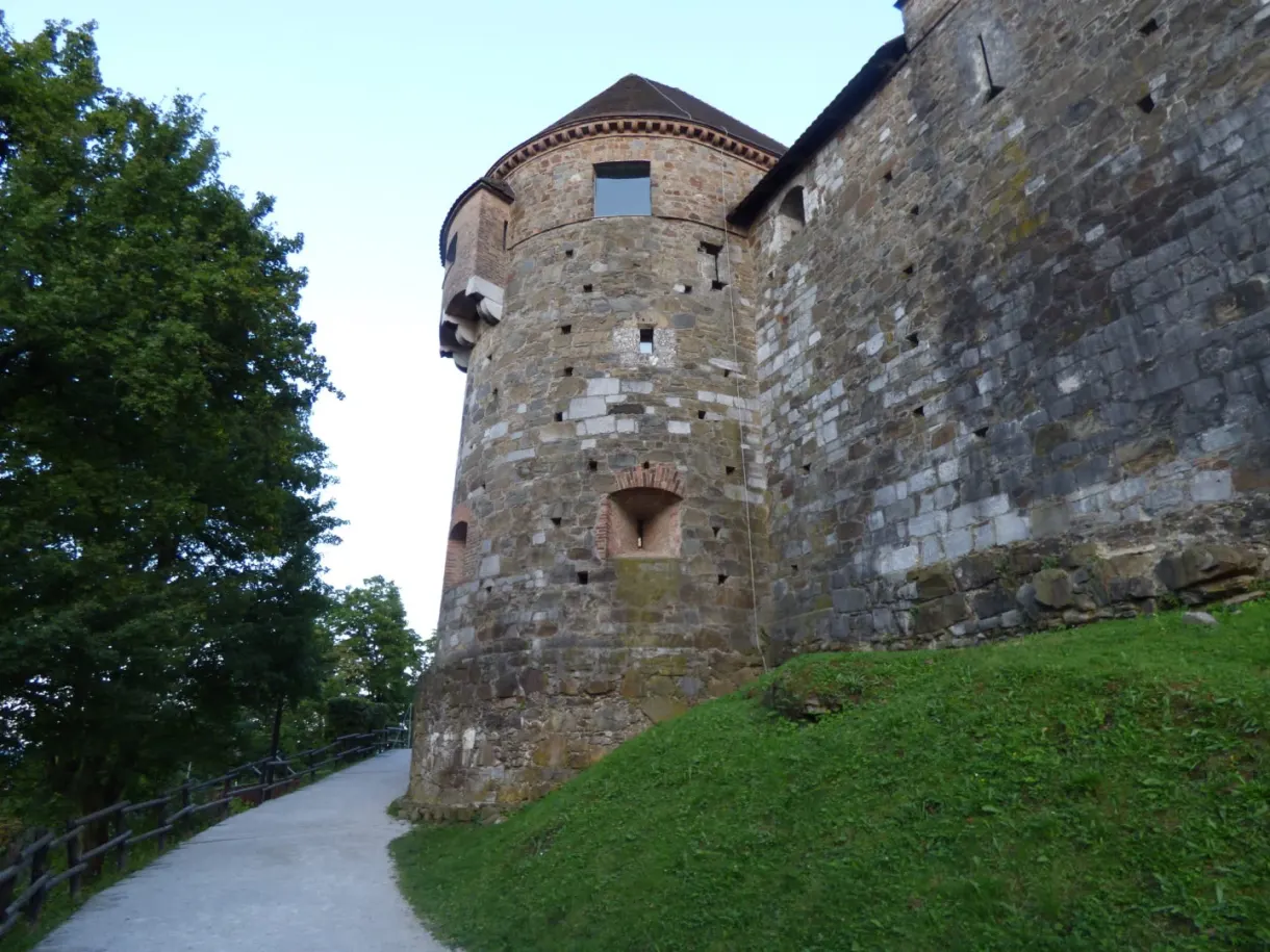 Tour ronde en pierre du château au-dessus d'un talus herbeux