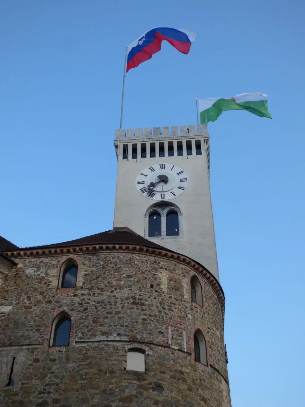 Tour de guet blanche et drapeaux slovènes en contre-plongée