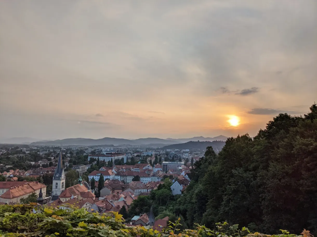 Coucher de soleil orangé sur la ville depuis la colline boisée