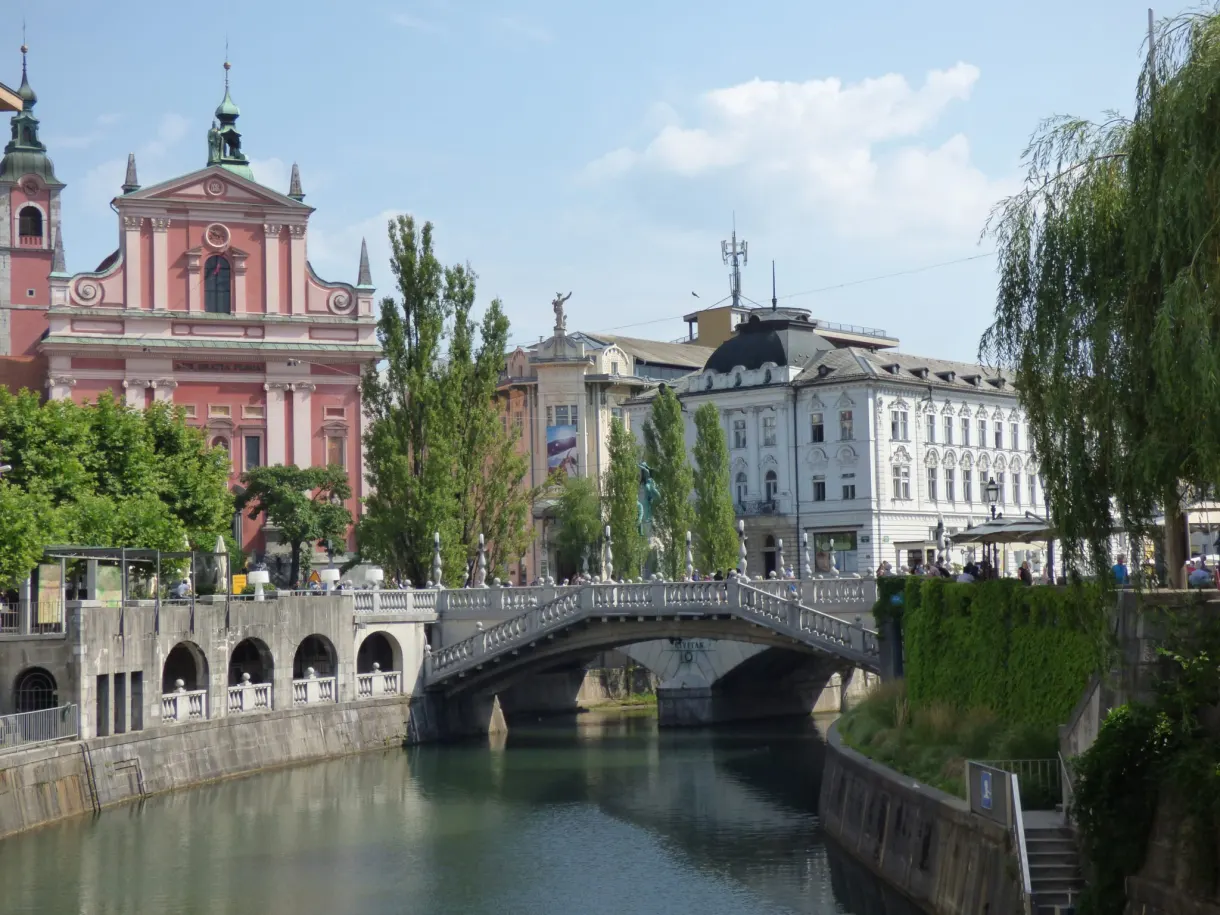 Église rose et pont blanc reflétés dans l'eau verte