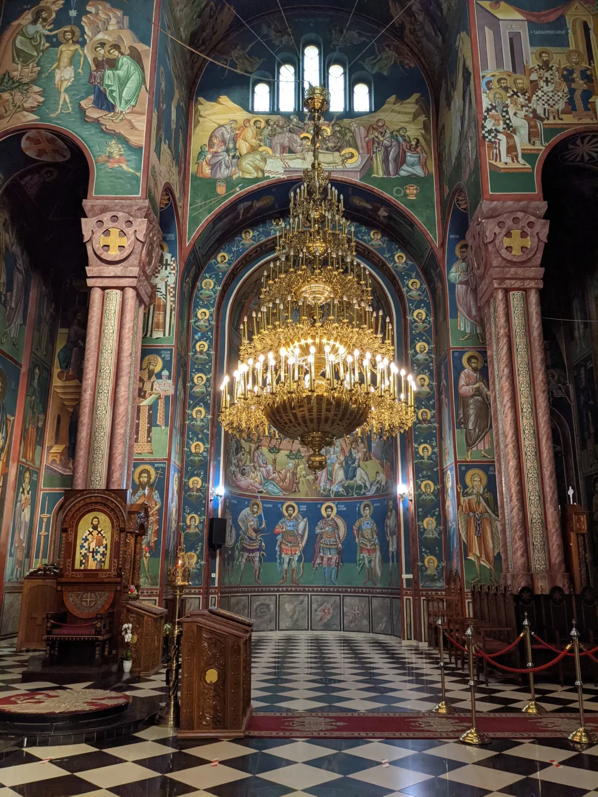 Lustre doré et fresques d'une église orthodoxe au sol en damier