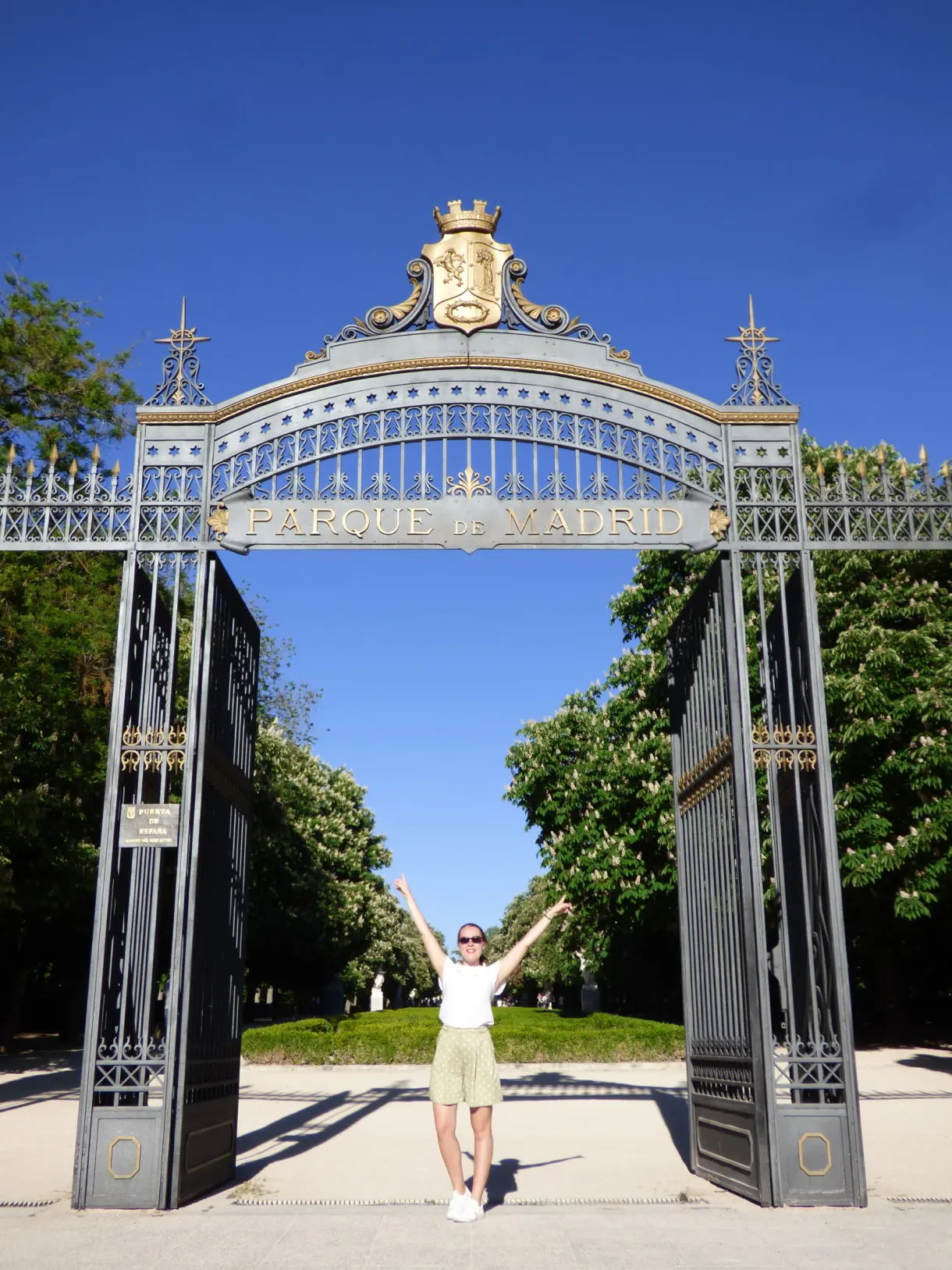 Portail en fer forgé du parc, bras levés sous l'arche