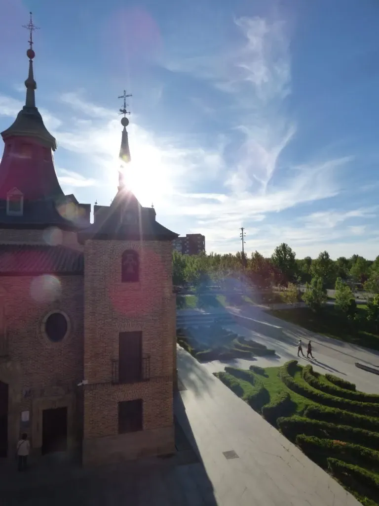 Clocher à contre-jour et soleil éclatant au-dessus des jardins