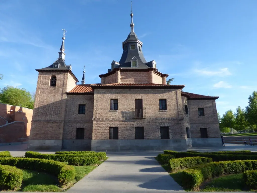 Bâtiment de brique à deux tours d'ardoise dans son jardin