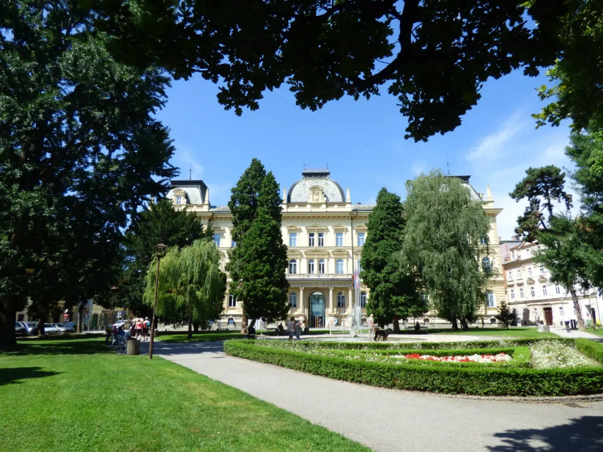Parc arboré devant un grand bâtiment jaune