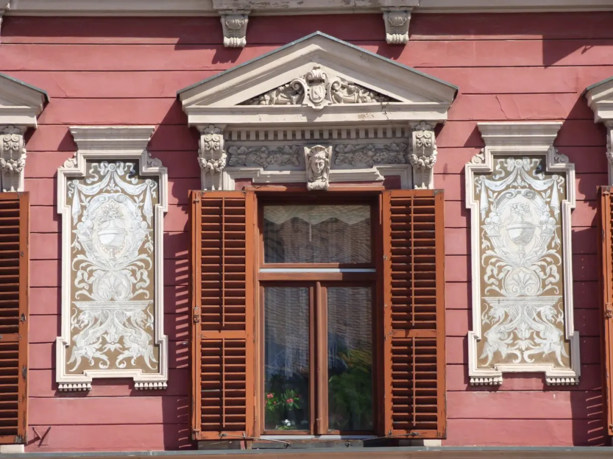 Fenêtre à stucs blancs sur une façade rose