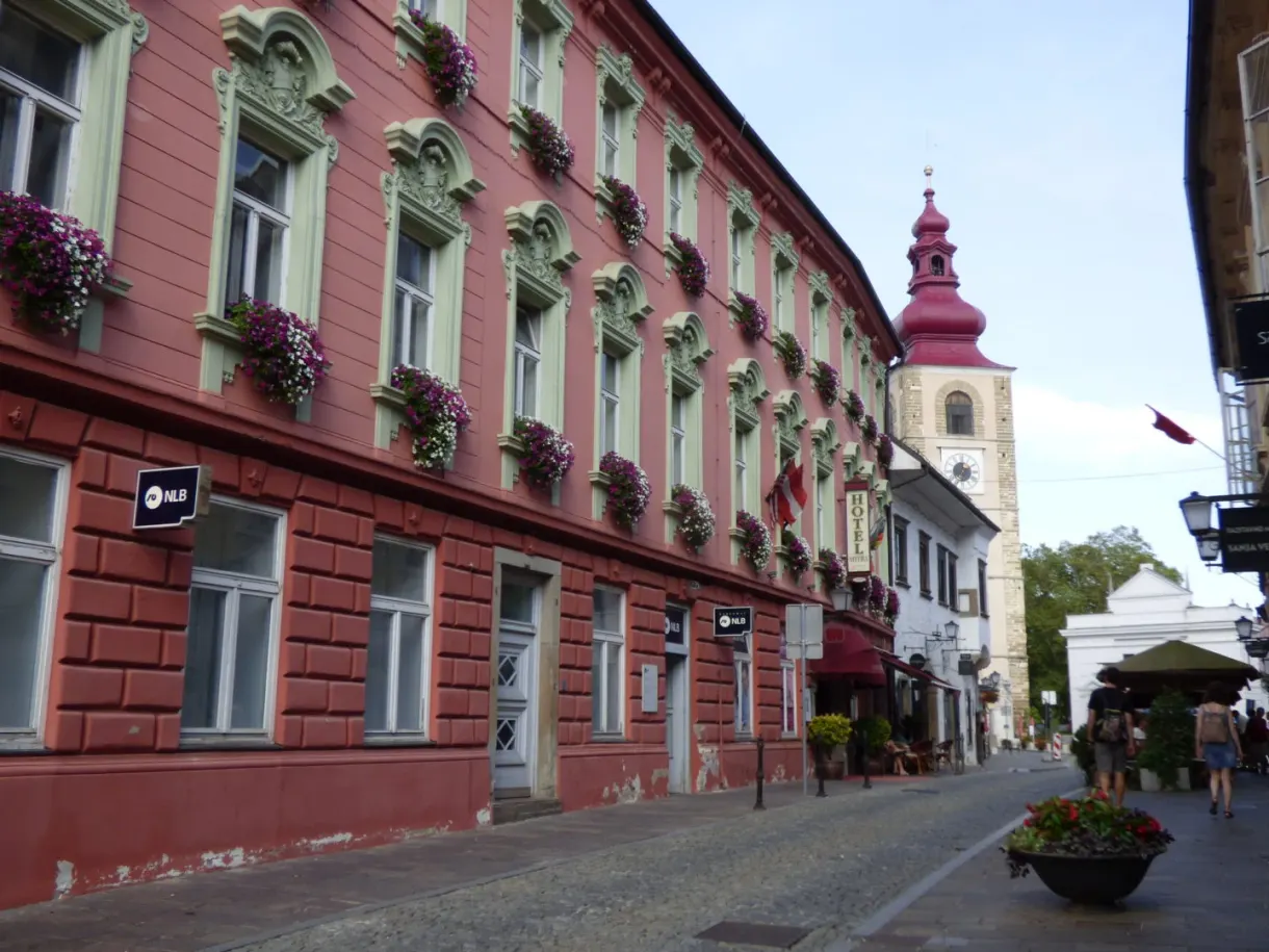 Rue pavée bordée d'un long bâtiment rouge, clocher au bout