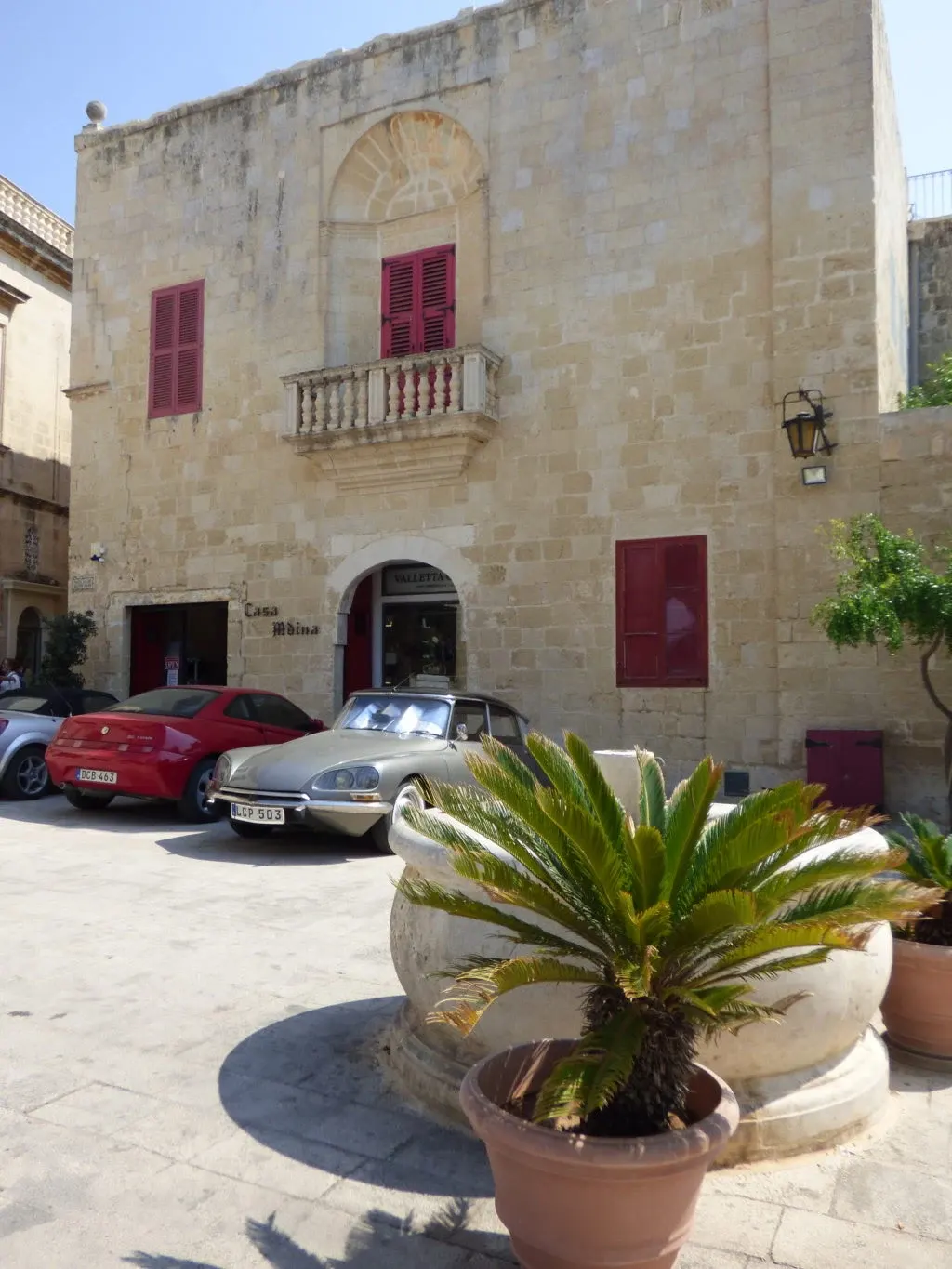 Volets rouges et voitures anciennes devant un palais
