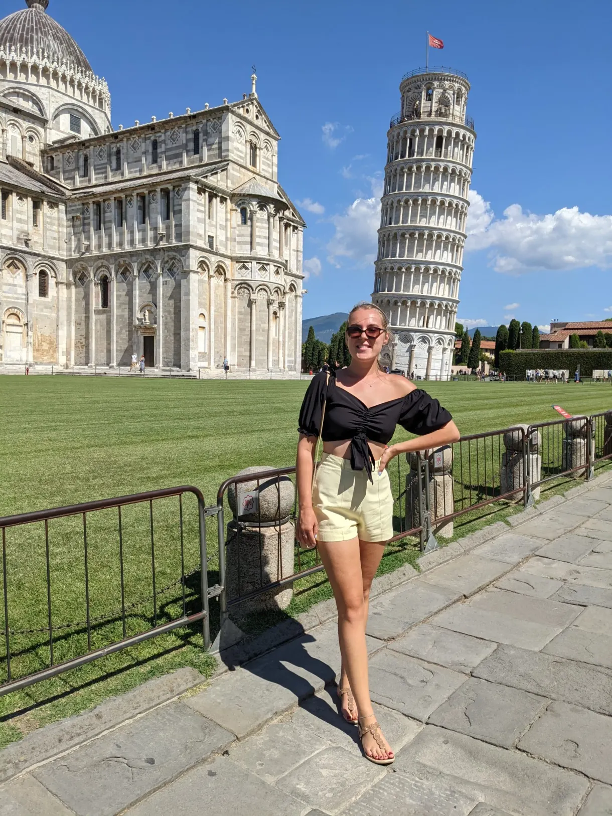 Femme posant devant la tour penchée et la cathédrale