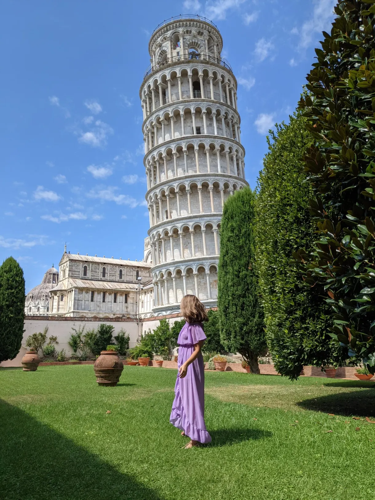 Femme en robe violette sur la pelouse au pied de la tour