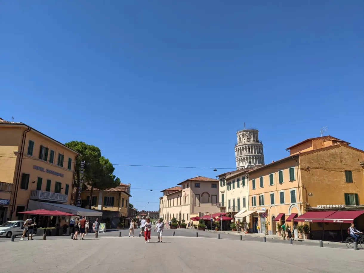 Tour penchée aperçue au bout d'une place bordée de terrasses
