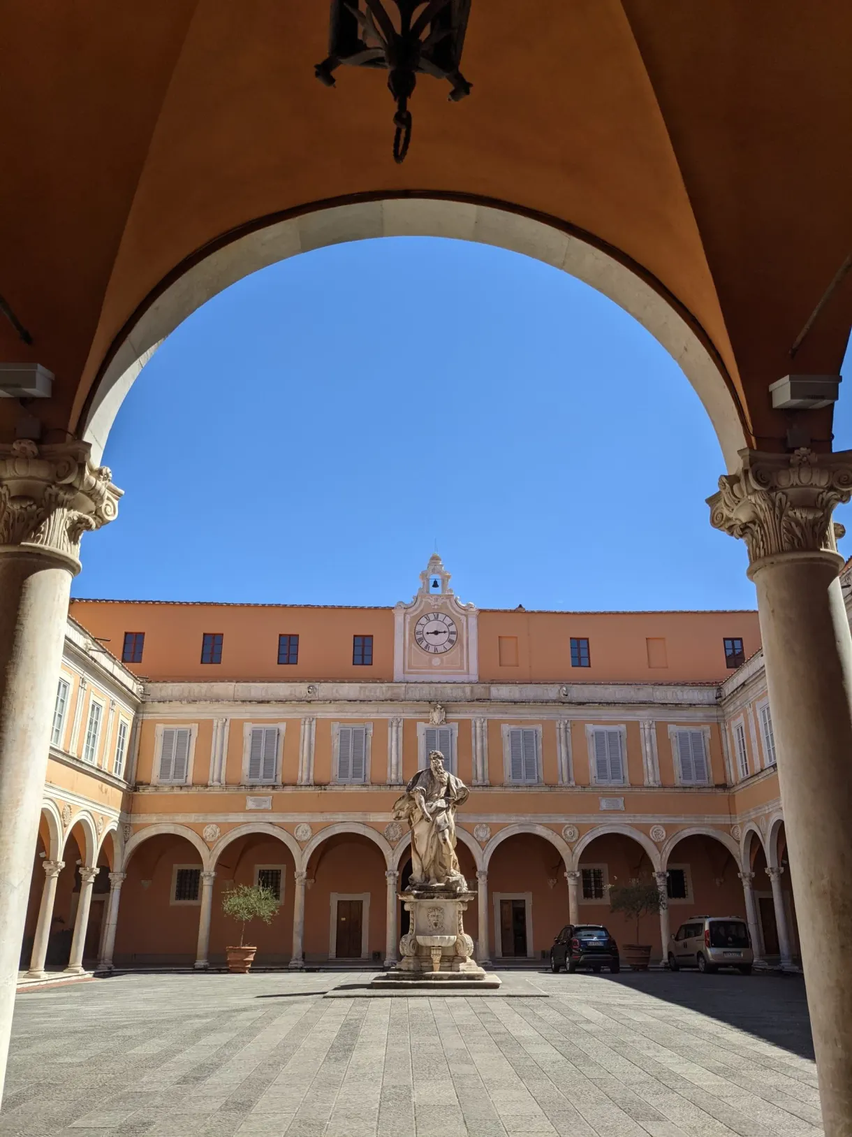 Arcade encadrant une cour à statue et horloge