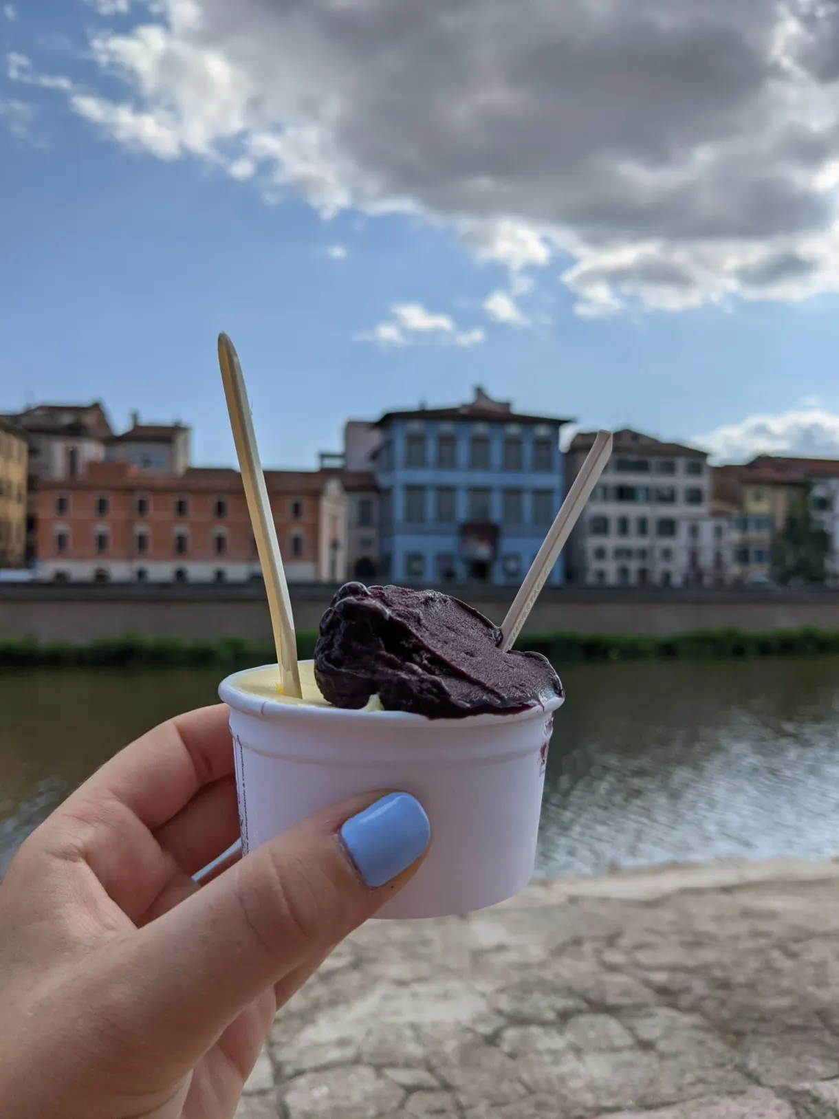 Pot de glace au chocolat tenu devant les quais de l'Arno
