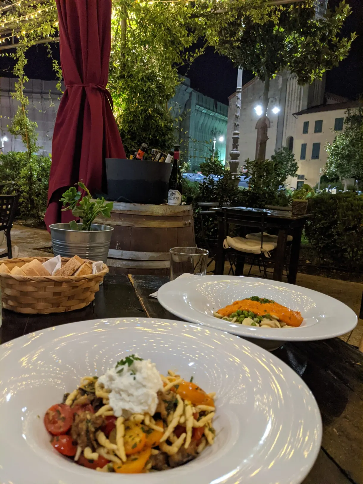 Deux assiettes de pâtes sur une table en terrasse le soir