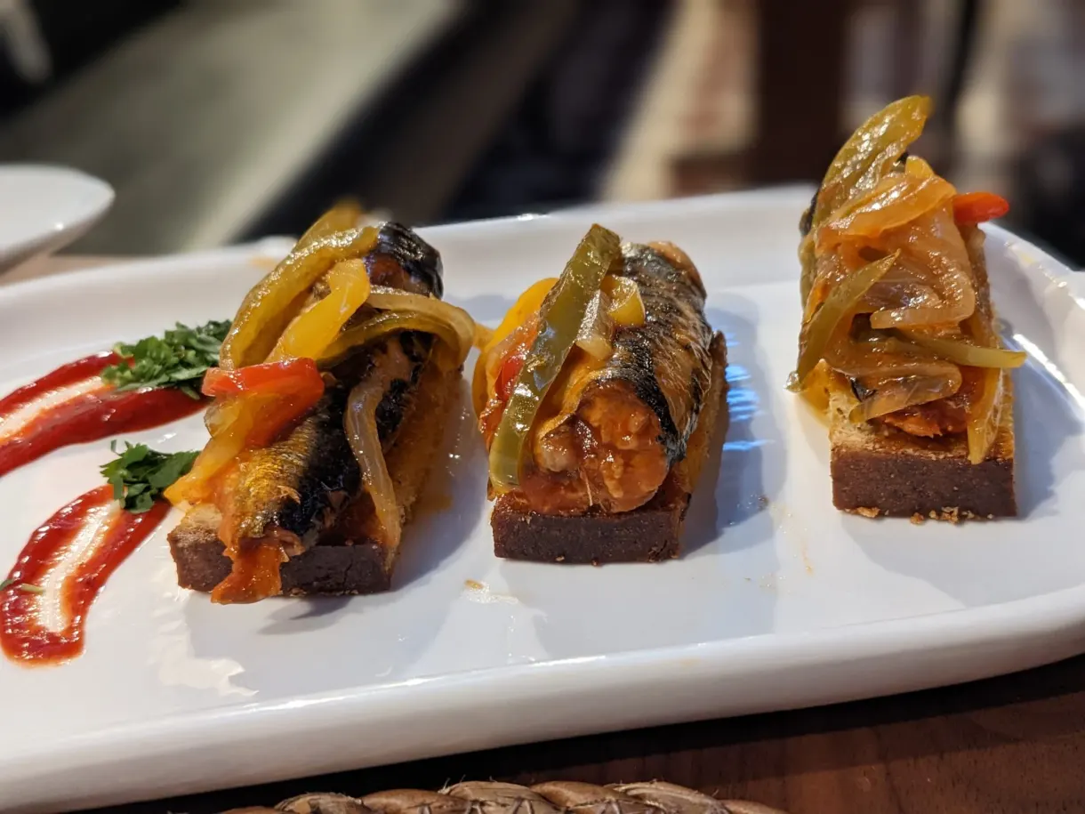 Toasts de sardines et poivrons marinés sur assiette blanche