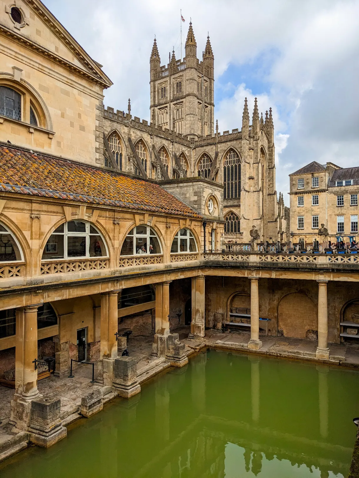 Thermes romains de Bath avec l'eau verte au soleil en arrière-plan l'abbaye