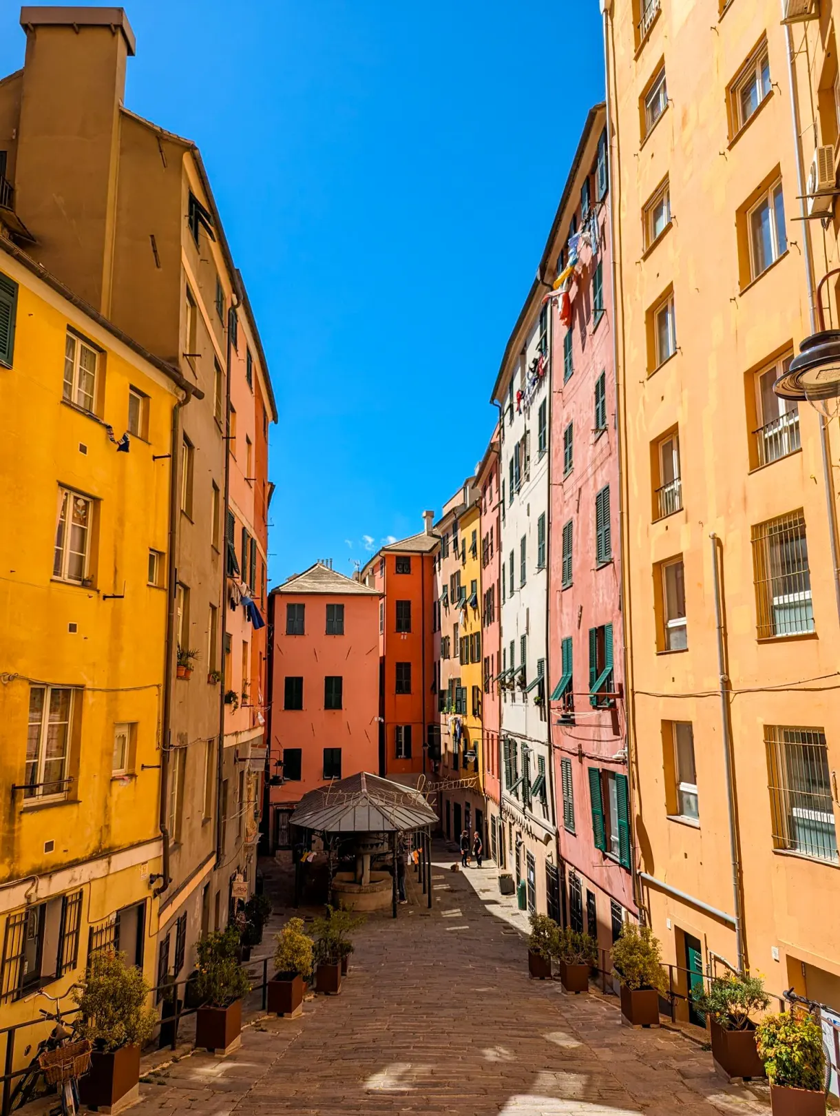Ruelle étroite bordée de façades ocre et rose à Gênes