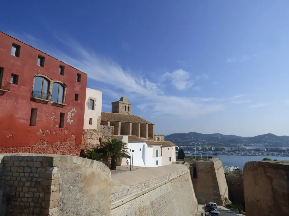 Façade rouge vif adossée aux remparts au-dessus du port
