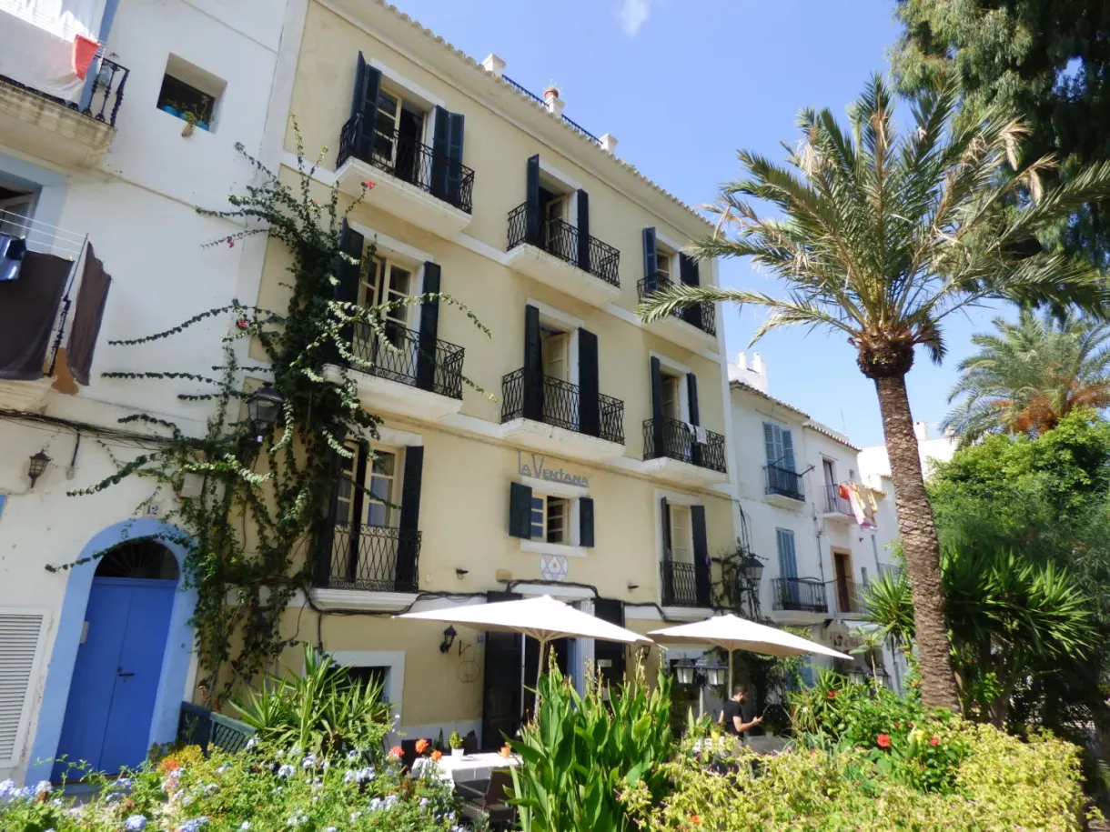 Immeuble jaune à balcons de fer et terrasse ombragée