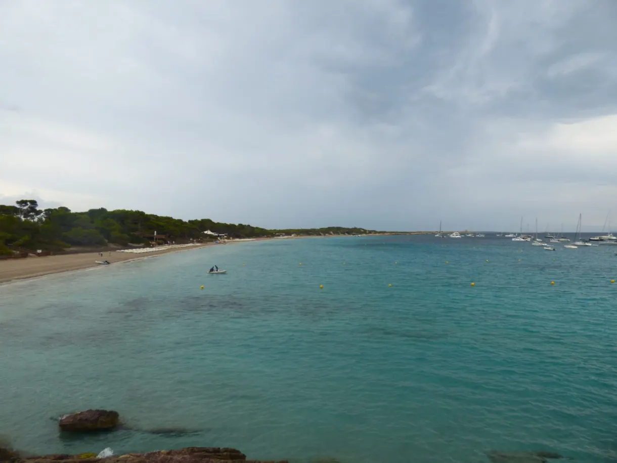 Baie turquoise bordée de pins et de sable clair