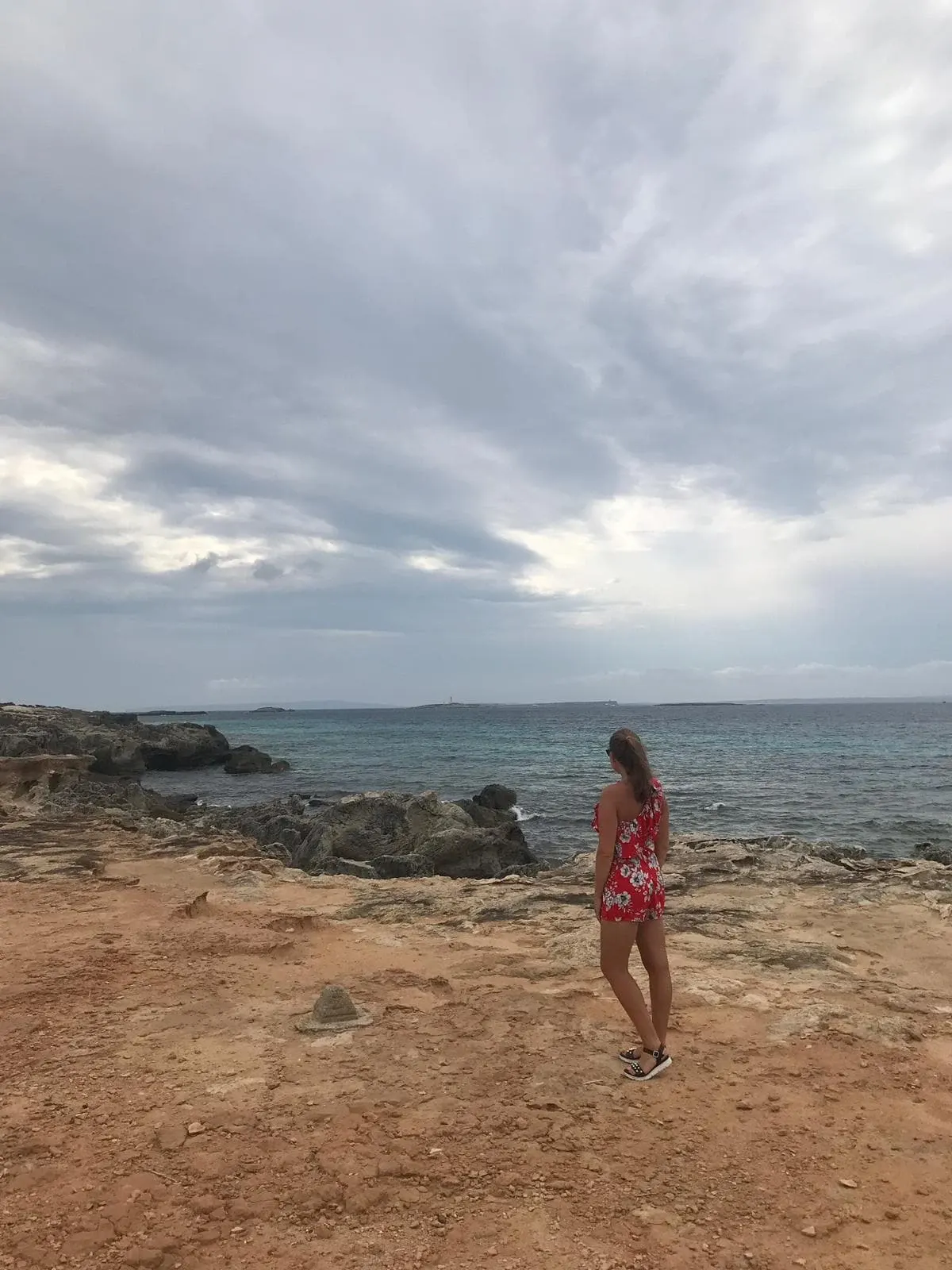 Silhouette en robe rouge sur une plage de sable et de roche