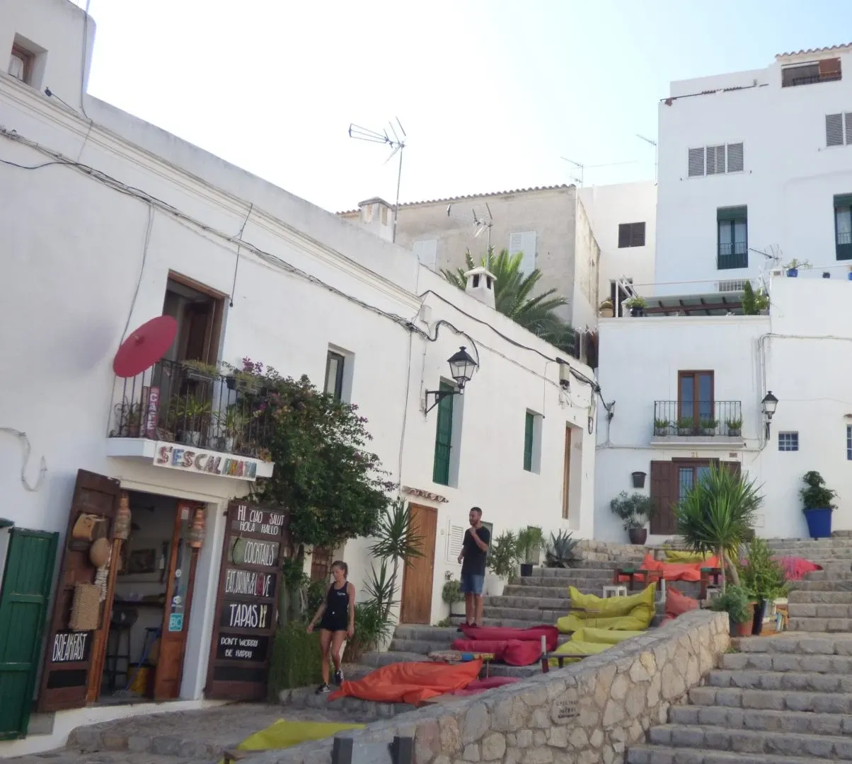Coussins colorés posés sur les marches devant un restaurant blanc