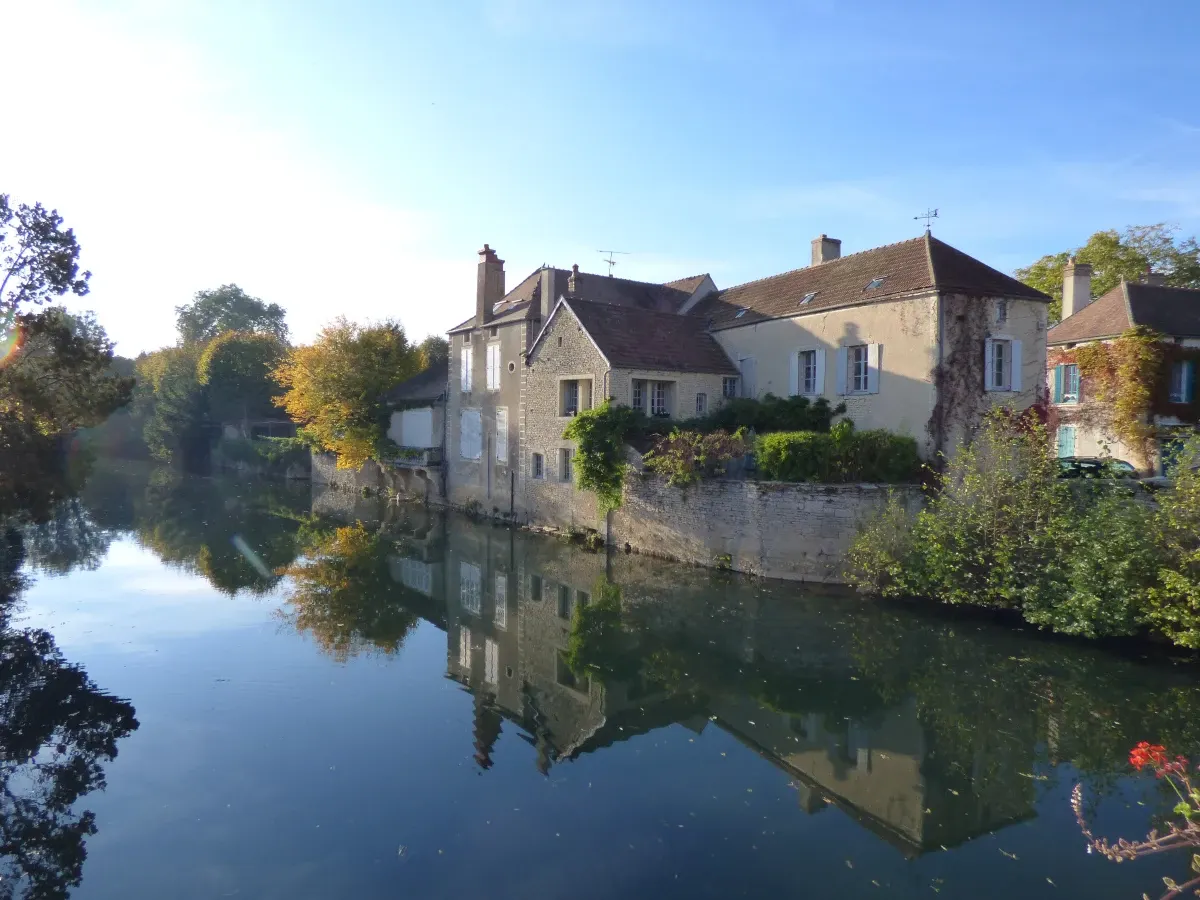 Maisons anciennes reflétées dans la rivière bordée d'arbres