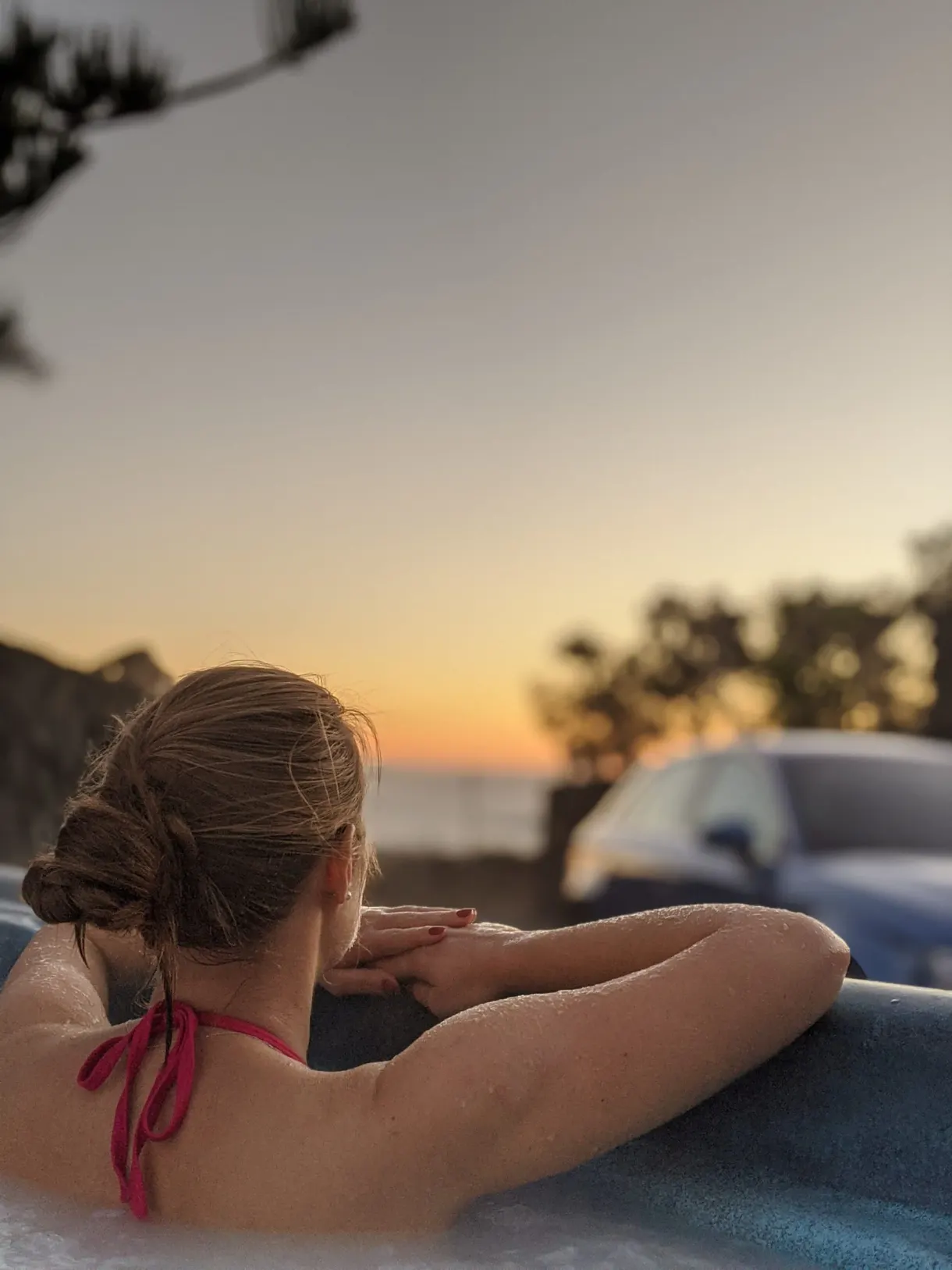 Femme de dos dans le jacuzzi face au soleil couchant