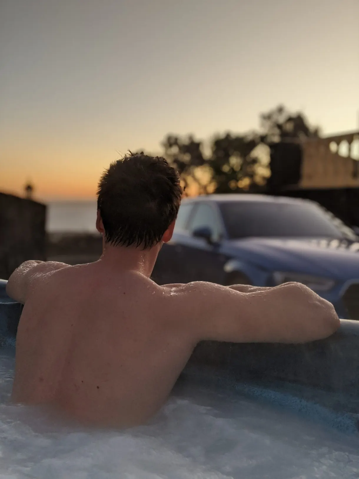 Homme de dos dans le jacuzzi au crépuscule