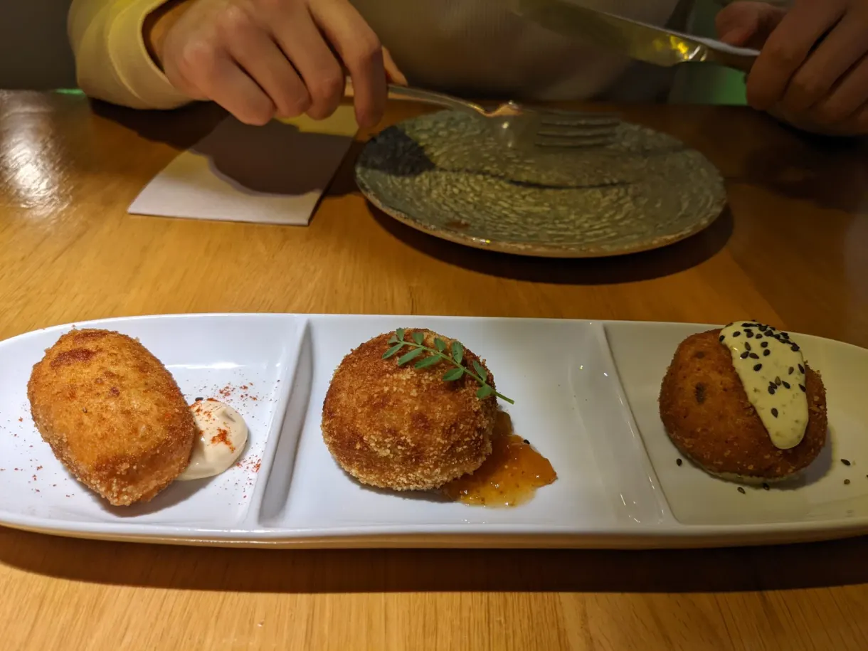 Trois croquettes dorées dans l'assiette, fourchette à la main