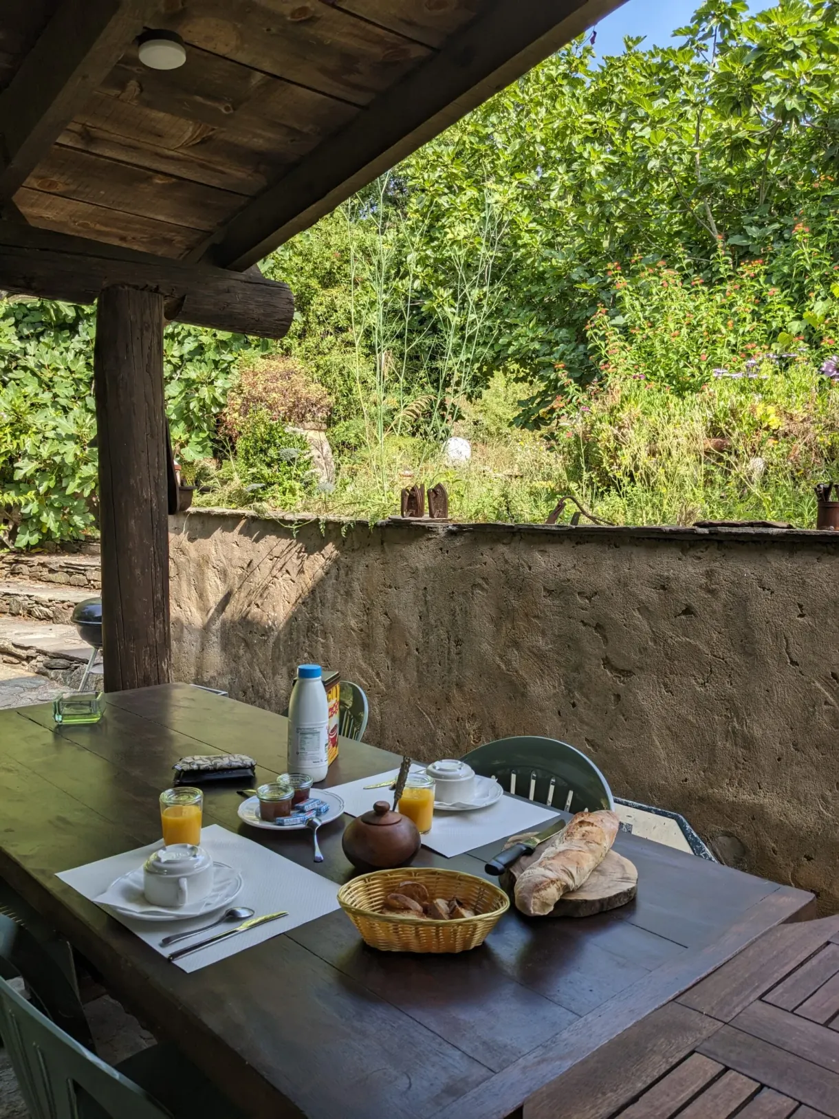 Petit-déjeuner dressé sous un auvent de pierre et de bois