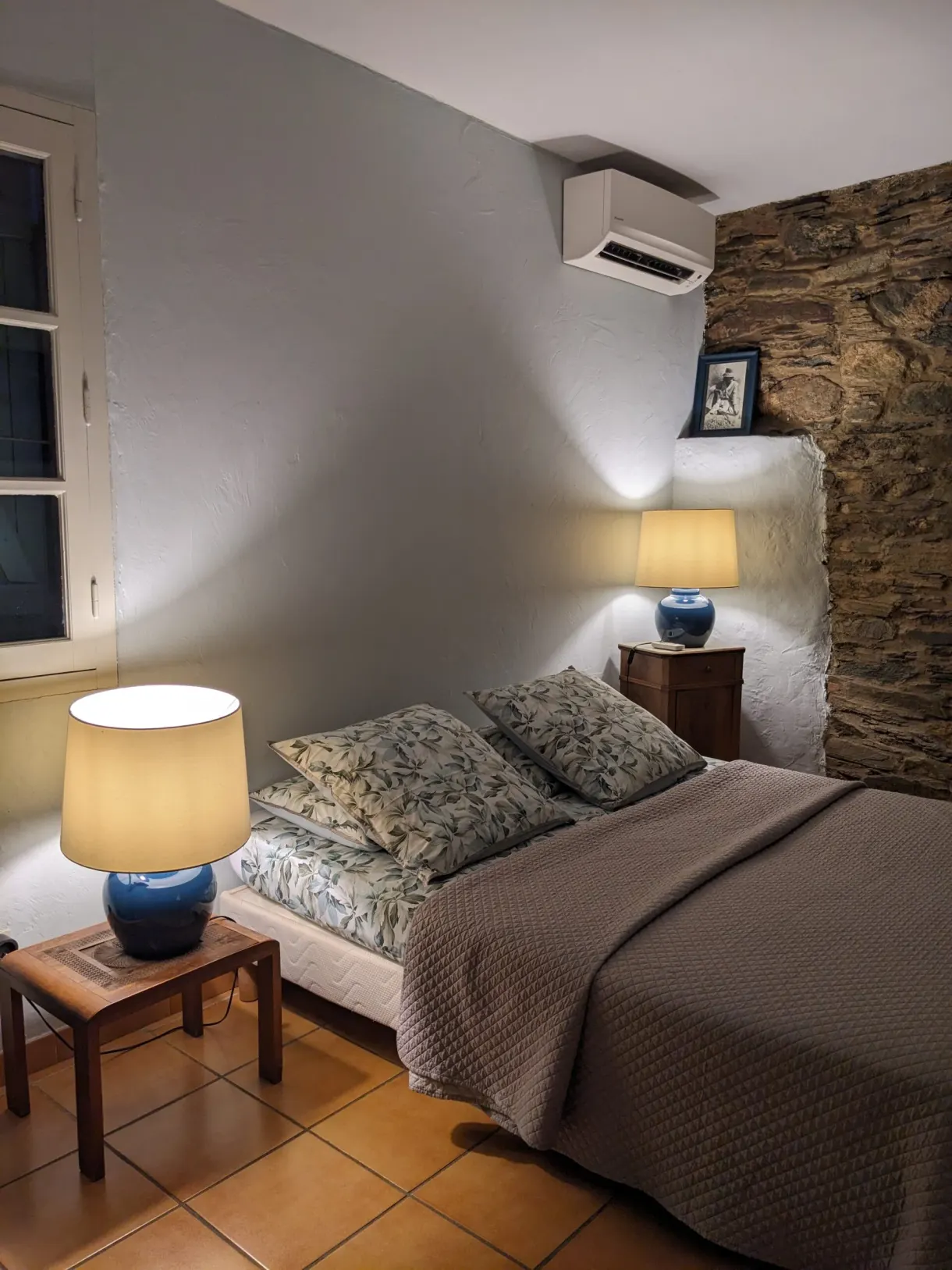Chambre aux murs de pierre éclairée par deux lampes de chevet