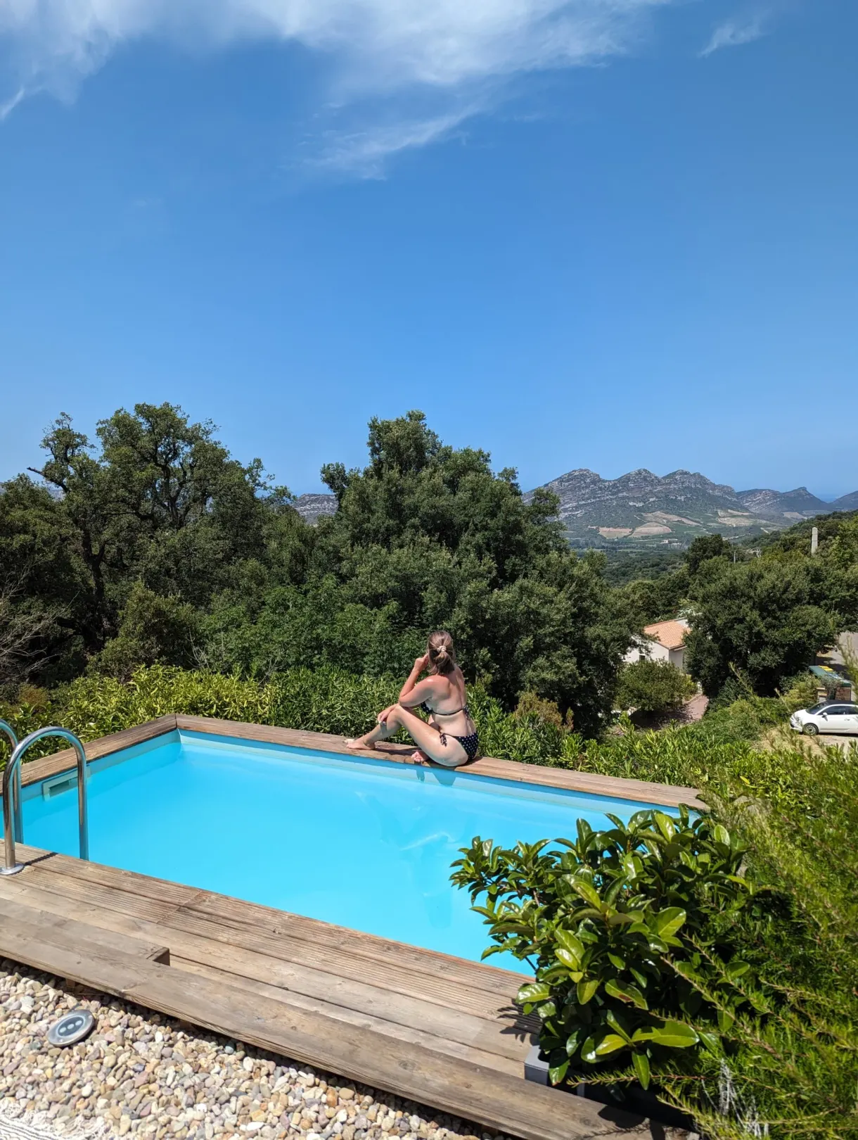 Baigneuse assise au bord du bassin face aux montagnes