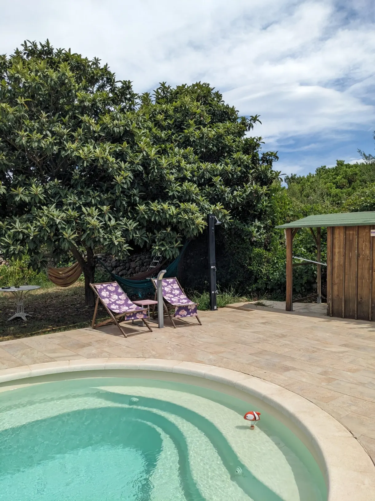 Piscine arrondie, transats rayés et hamac à l'ombre