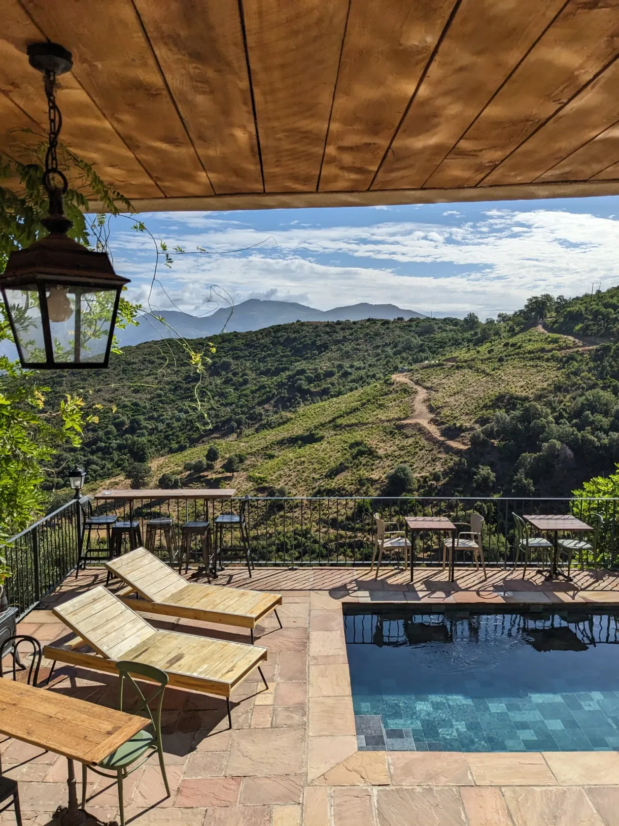 Terrasse couverte, transats et piscine face aux collines